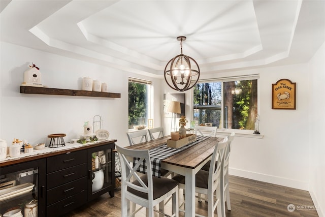 dining area with a chandelier, a tray ceiling, wine cooler, and dark wood-type flooring