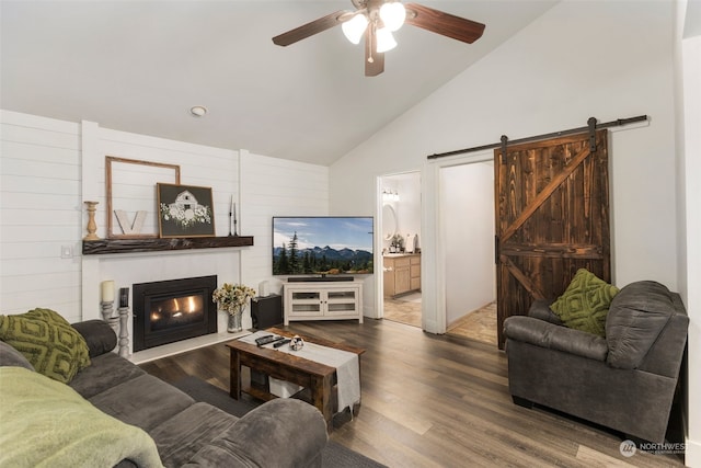 living room with high vaulted ceiling, hardwood / wood-style floors, ceiling fan, and a barn door