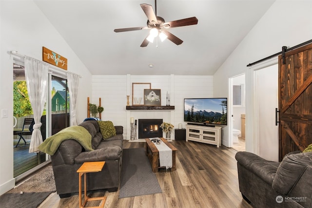 living room with a large fireplace, dark wood-type flooring, vaulted ceiling, and a barn door