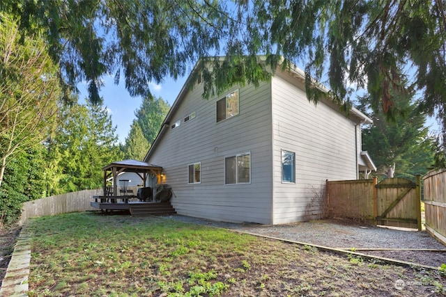 back of property with a lawn, a wooden deck, and a gazebo