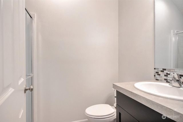 bathroom featuring tasteful backsplash, baseboards, toilet, an enclosed shower, and vanity