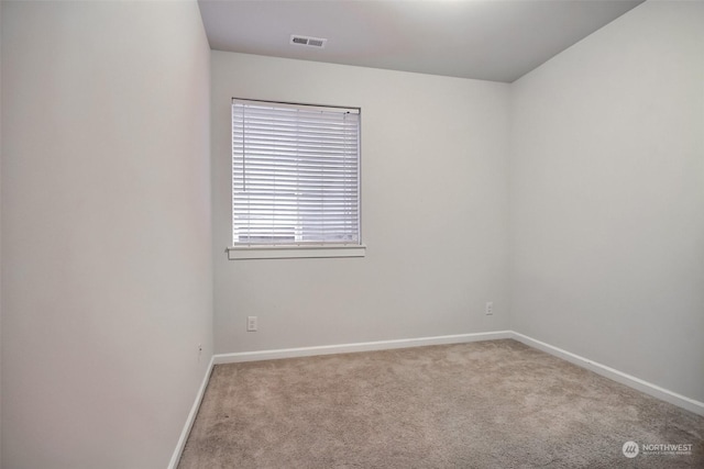 spare room featuring carpet, visible vents, and baseboards