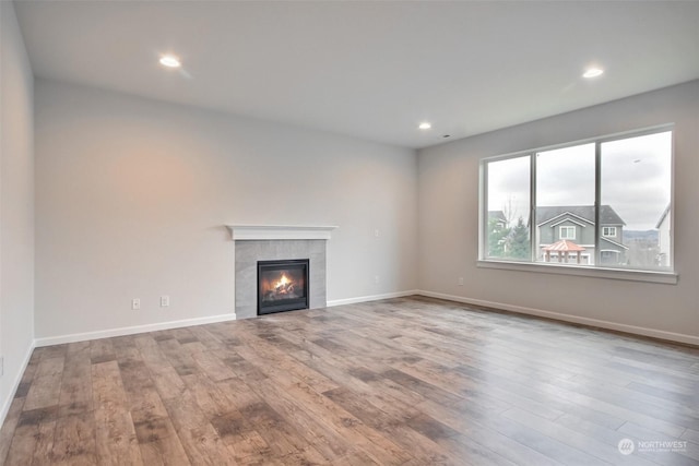 unfurnished living room with a fireplace, baseboards, wood finished floors, and recessed lighting