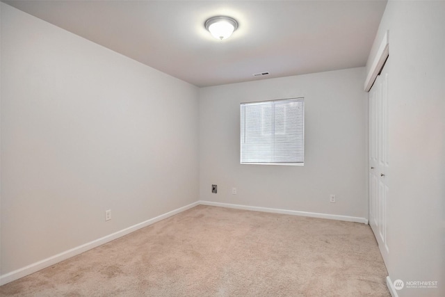 spare room with baseboards, visible vents, and light colored carpet