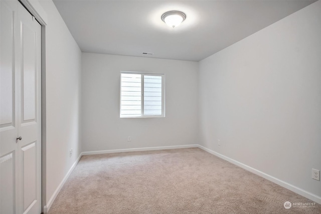 carpeted spare room featuring visible vents and baseboards