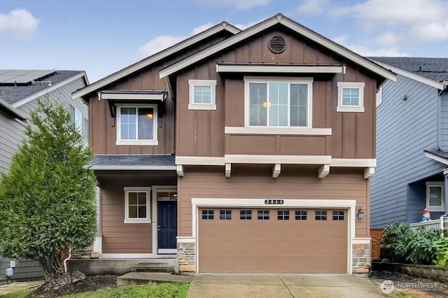 craftsman inspired home with board and batten siding, concrete driveway, an attached garage, and stone siding