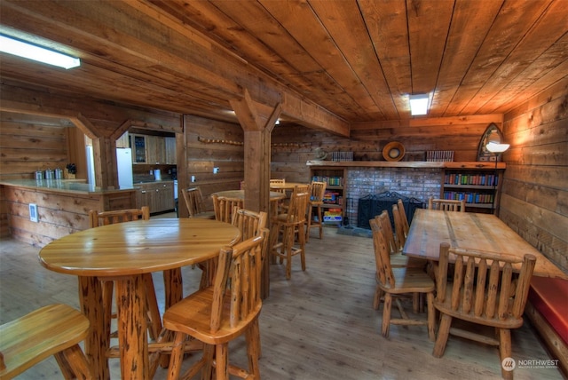 dining area with wood ceiling, wood walls, a fireplace, and wood-type flooring