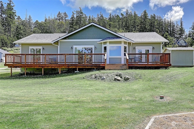 rear view of house featuring a wooden deck, a lawn, french doors, and a storage unit