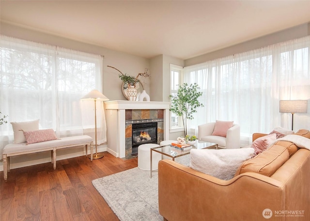 living area featuring a tiled fireplace, wood finished floors, and baseboards