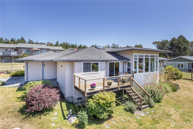 rear view of house with a deck and a yard