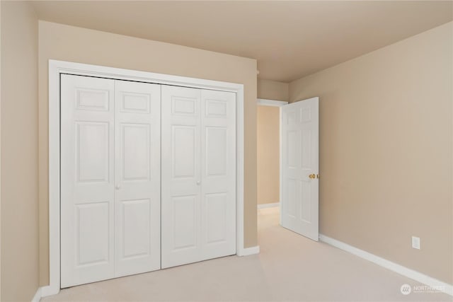 unfurnished bedroom featuring a closet and light colored carpet