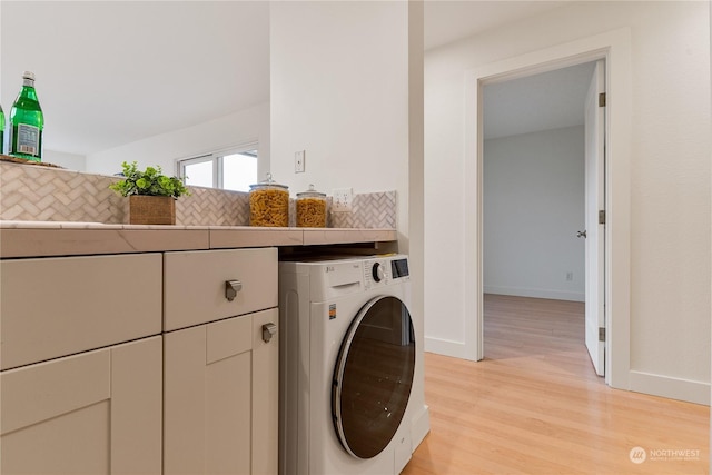 clothes washing area with washer / dryer, cabinets, and light hardwood / wood-style flooring