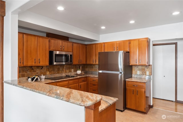 kitchen with light stone counters, decorative backsplash, kitchen peninsula, and appliances with stainless steel finishes