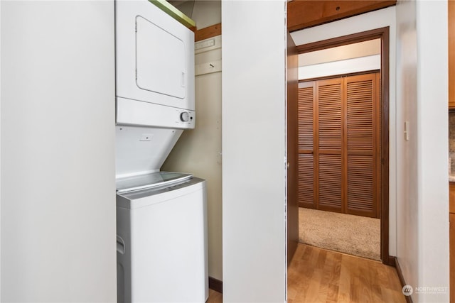 clothes washing area with stacked washer and dryer and light wood-type flooring