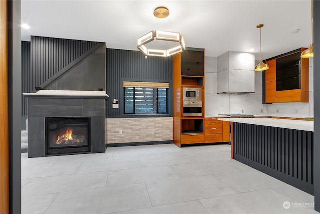 kitchen featuring hanging light fixtures, wall chimney exhaust hood, and stainless steel appliances