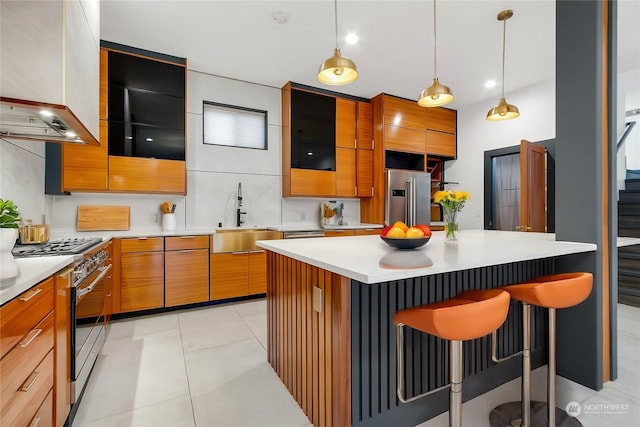 kitchen with high end appliances, a center island, decorative light fixtures, a kitchen bar, and sink