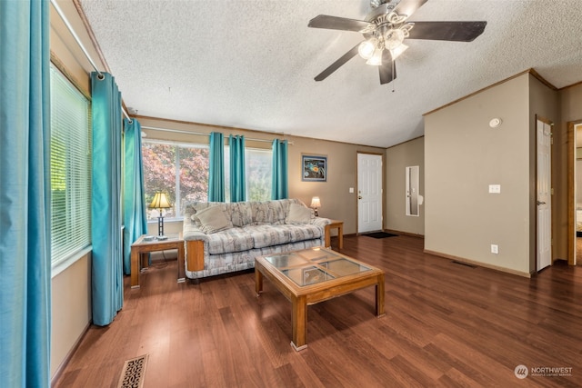 living room featuring lofted ceiling, ceiling fan, dark hardwood / wood-style floors, ornamental molding, and a textured ceiling