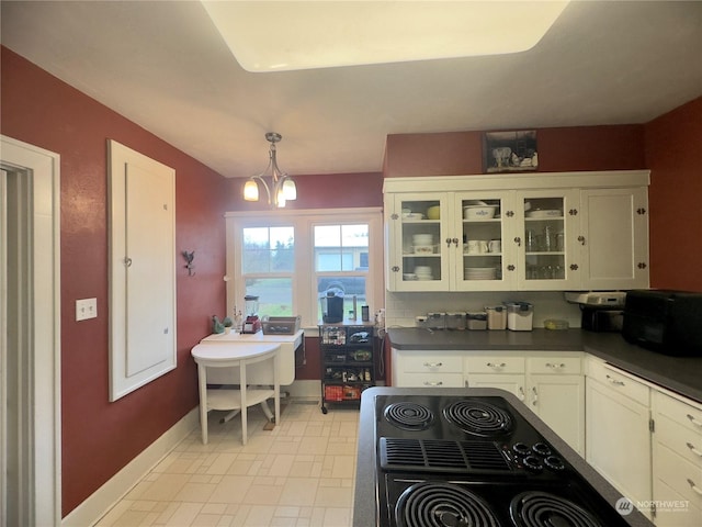 kitchen with hanging light fixtures, white cabinets, range, and a notable chandelier