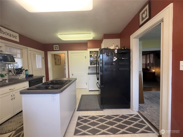 kitchen with light tile patterned flooring, white cabinetry, a center island, and black appliances