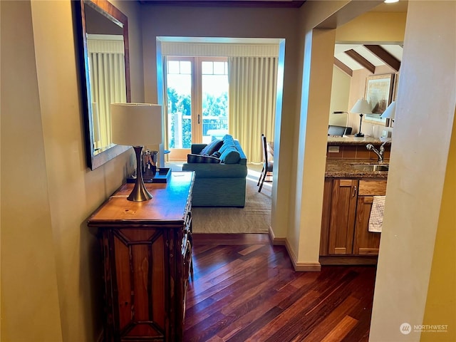 hallway featuring beam ceiling, dark hardwood / wood-style floors, french doors, and sink