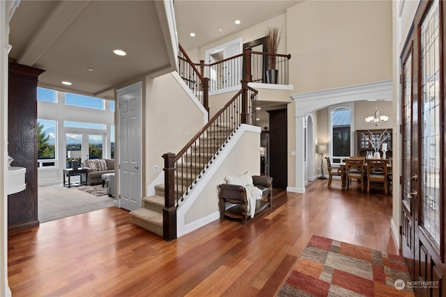 foyer entrance with hardwood / wood-style flooring, a high ceiling, a chandelier, and french doors