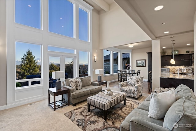 carpeted living room with a towering ceiling, sink, and french doors