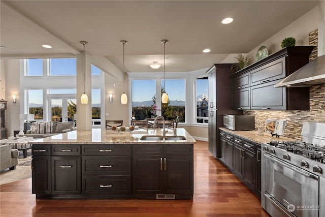 kitchen featuring sink, tasteful backsplash, hanging light fixtures, stainless steel appliances, and wall chimney range hood