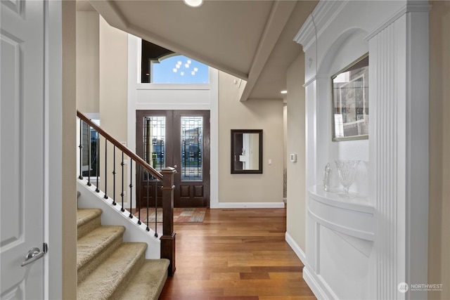 foyer entrance featuring hardwood / wood-style flooring, vaulted ceiling, and french doors