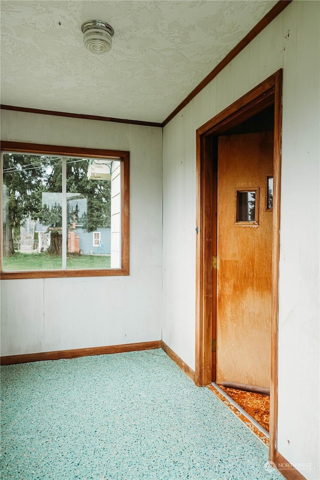 unfurnished room with ornamental molding and wooden walls