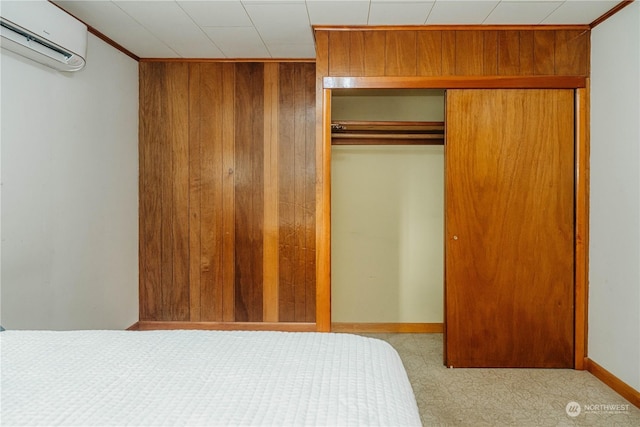 bedroom with light colored carpet, wooden walls, a closet, and an AC wall unit