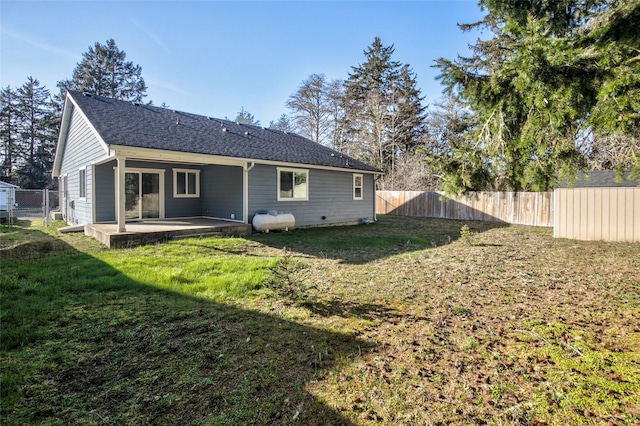 rear view of property featuring a yard, roof with shingles, a patio area, and a fenced backyard