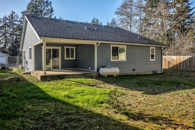 back of house with a yard, roof with shingles, and fence