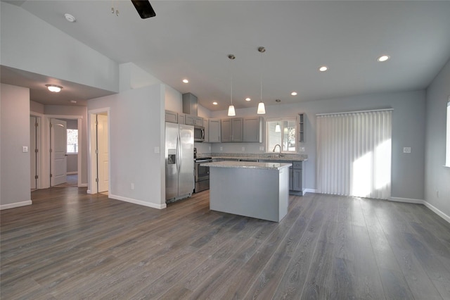 kitchen featuring lofted ceiling, dark wood-style flooring, a center island, stainless steel appliances, and a sink