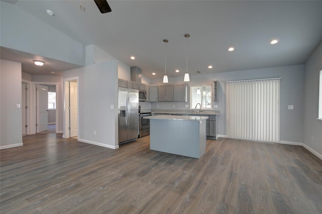 kitchen featuring dark wood-style floors, a center island, stainless steel appliances, lofted ceiling, and a sink