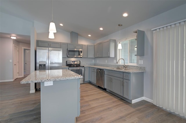 kitchen featuring gray cabinets, appliances with stainless steel finishes, a sink, vaulted ceiling, and a kitchen island