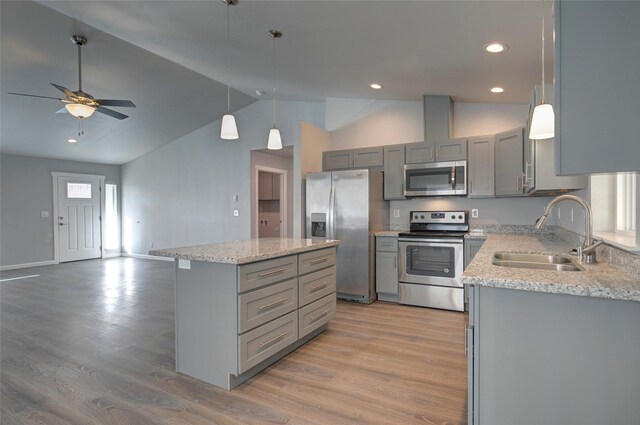 kitchen featuring a kitchen island, appliances with stainless steel finishes, gray cabinetry, light wood-type flooring, and a sink