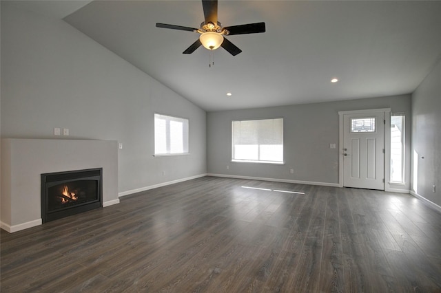 unfurnished living room featuring a warm lit fireplace, lofted ceiling, recessed lighting, dark wood-style flooring, and baseboards