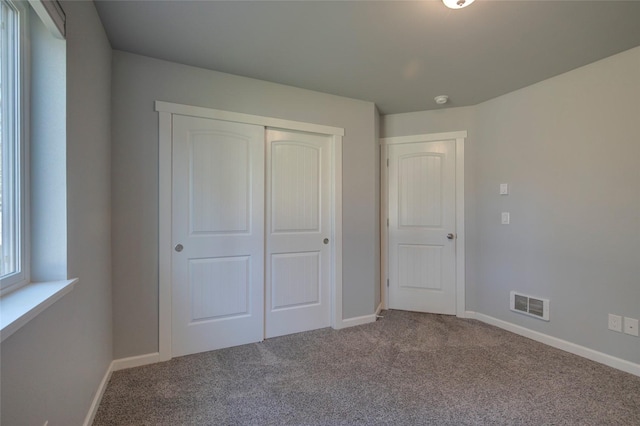 unfurnished bedroom featuring carpet floors, a closet, visible vents, and baseboards