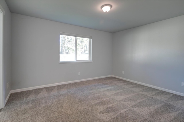 spare room featuring carpet floors and baseboards