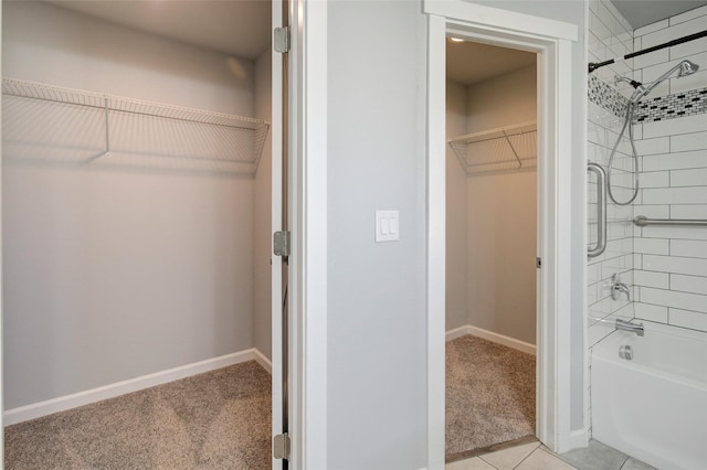 interior space featuring washtub / shower combination, baseboards, a walk in closet, and tile patterned floors