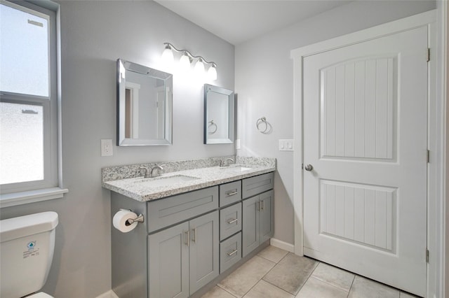 bathroom featuring double vanity, a sink, toilet, and tile patterned floors