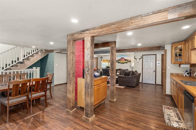 interior space with sink, dark wood-type flooring, dishwasher, a textured ceiling, and beamed ceiling