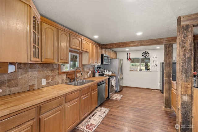 kitchen with a textured ceiling, appliances with stainless steel finishes, wood counters, light hardwood / wood-style floors, and sink