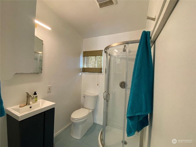 bathroom featuring tile patterned floors, toilet, vanity, and a shower with shower door