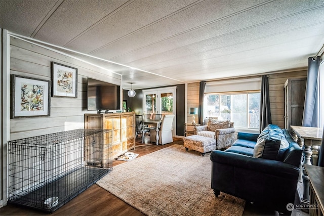 living room with a textured ceiling, wooden walls, and hardwood / wood-style floors