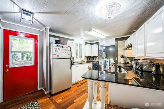 kitchen featuring stainless steel appliances, white cabinets, dark stone countertops, kitchen peninsula, and dark hardwood / wood-style floors