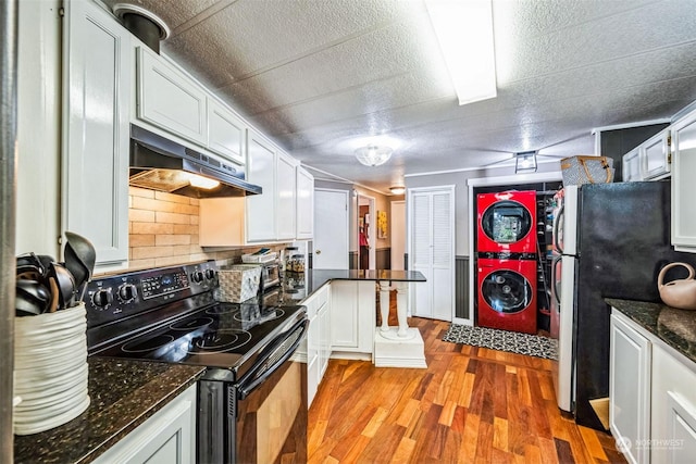 kitchen with white cabinets, light hardwood / wood-style floors, stacked washer / dryer, and black range with electric cooktop