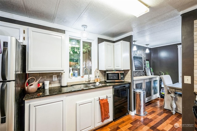 kitchen featuring appliances with stainless steel finishes, pendant lighting, hardwood / wood-style flooring, sink, and white cabinetry