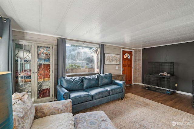 living room with a textured ceiling, dark hardwood / wood-style flooring, and wood walls