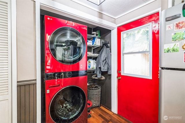 washroom with a textured ceiling, stacked washer / dryer, and dark wood-type flooring